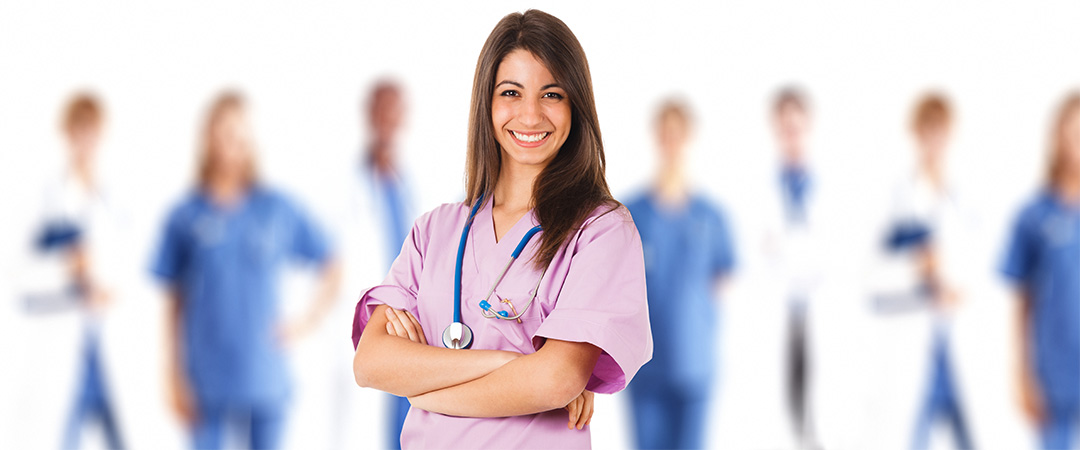 Team of nurses standing behind a lead nurse in pink scrubs