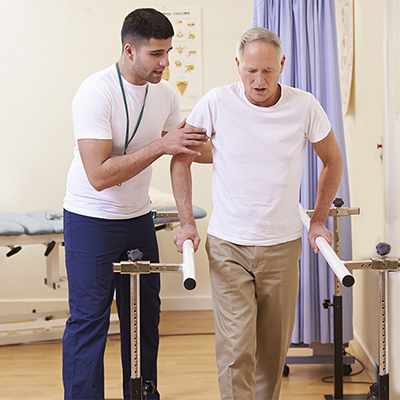 therapist helping a man on the assisted parallel walking bars